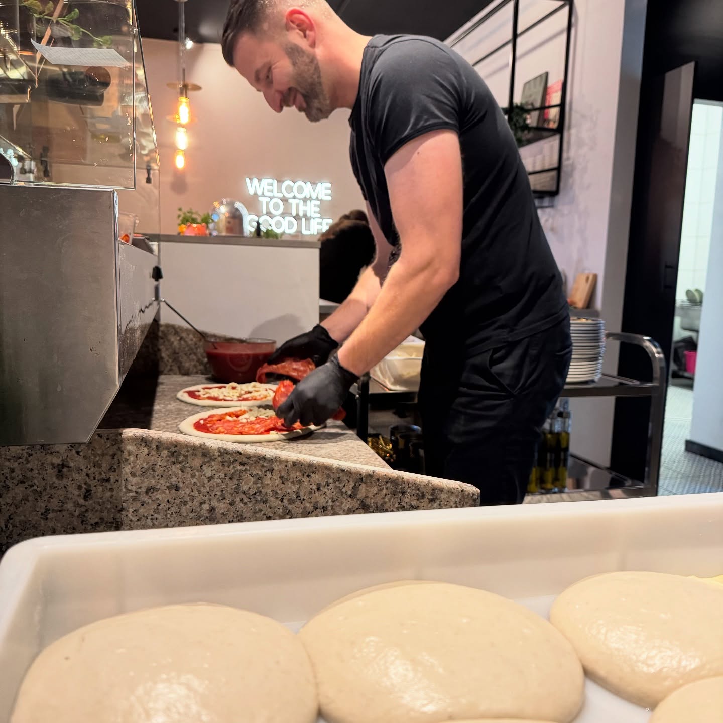 Pizzaiolo składa pizzę przy blacie