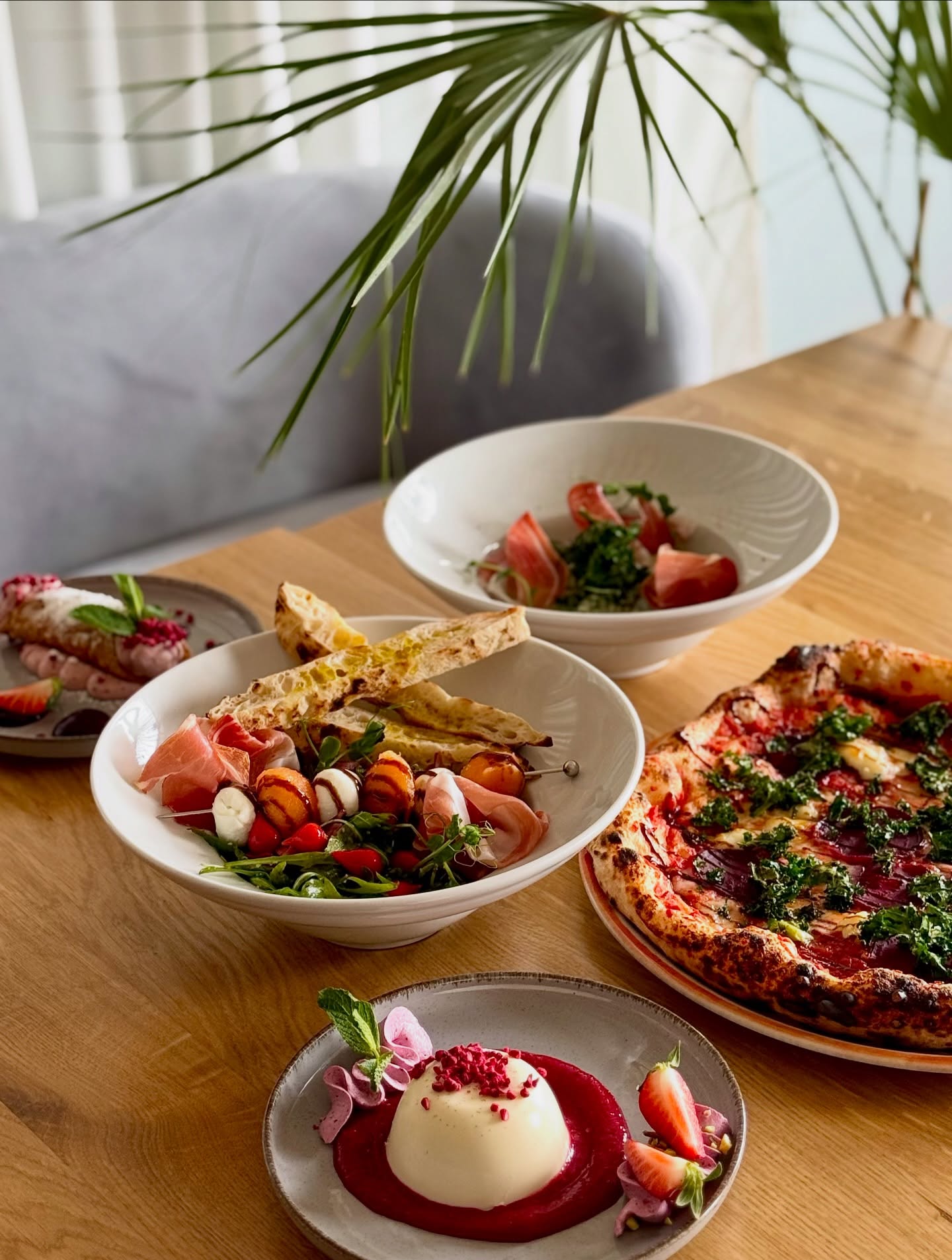 Stół pełen dań — pizza, antipasti i desery