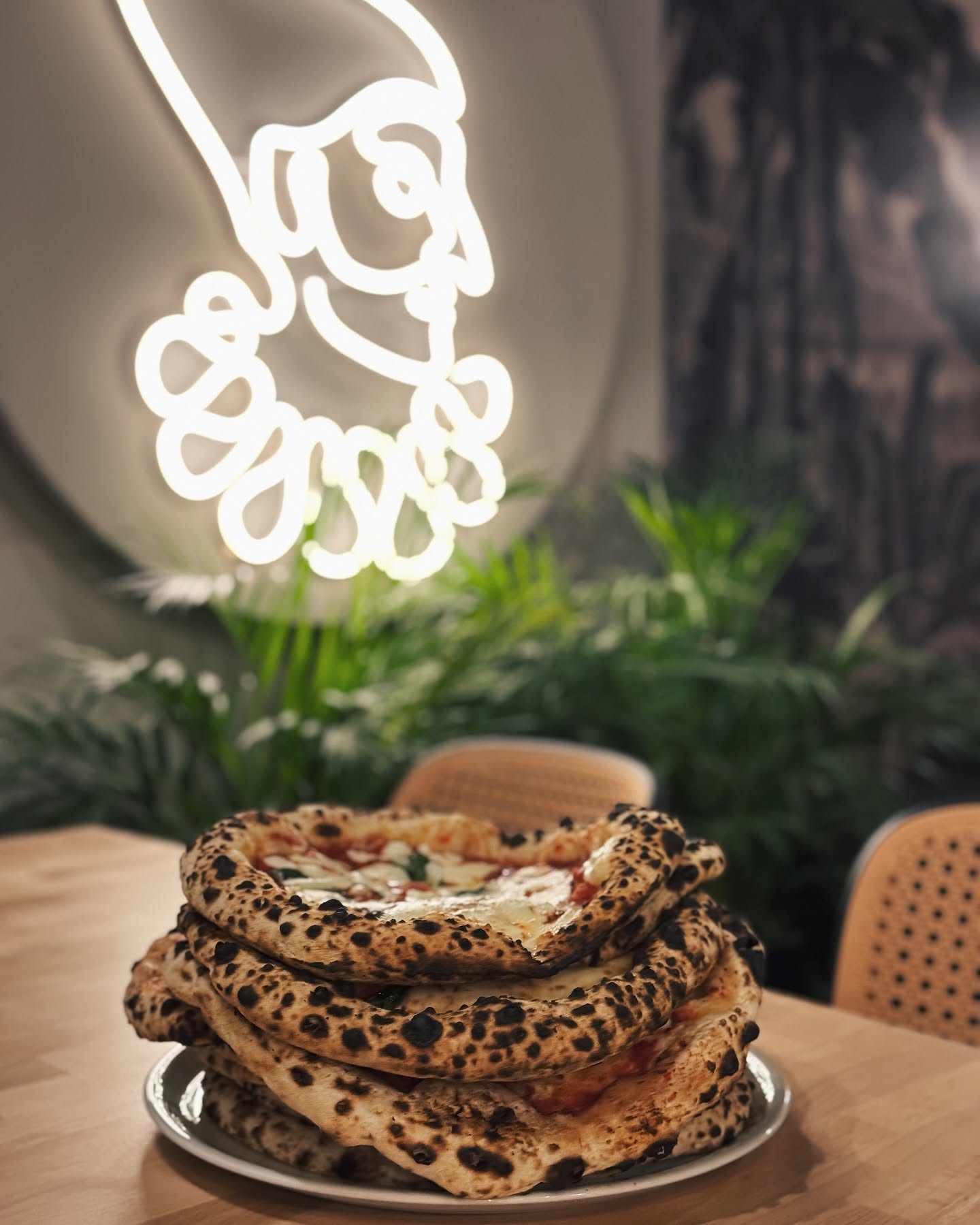 Stos pizz neapolitańskich pod neonowym logo FUMO