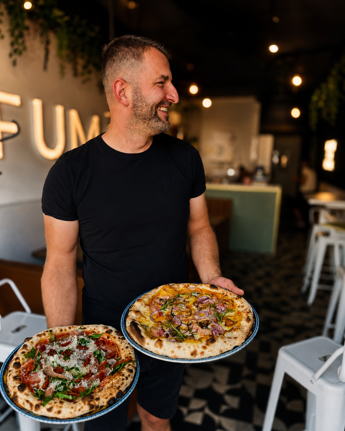 Pizzaiolo FUMO z dwiema pizzami neapolitańskimi we wnętrzu restauracji
